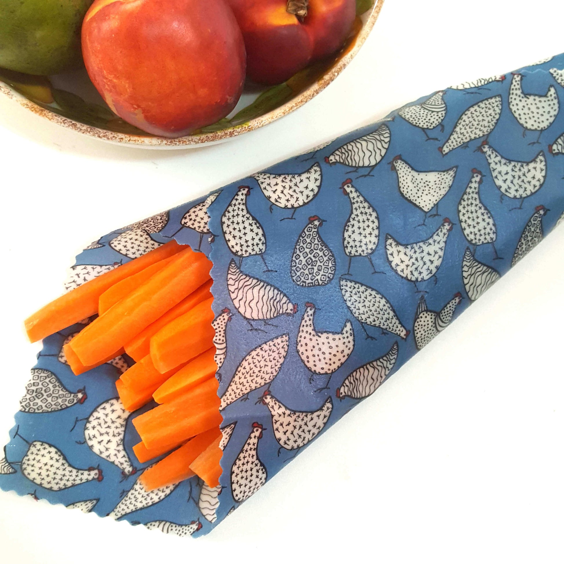Reusable Beeswax Food Wraps 100% Hand Made in the UK by Honey Bee Good. Planet-Kind single large beeswax wrap in Blue Hens pattern as flatlay with carrots