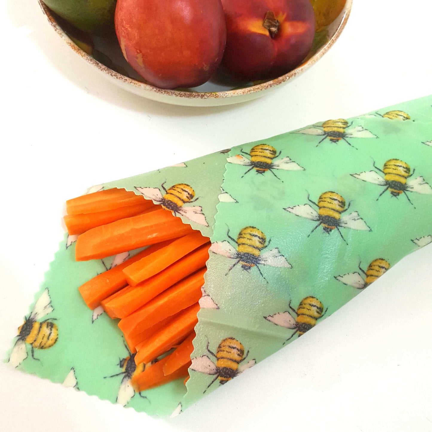 Reusable Beeswax Food Wraps 100% Hand Made in the UK by Honey Bee Good. Planet-Kind single large beeswax wrap in Green Bees pattern as flatlay with carrots