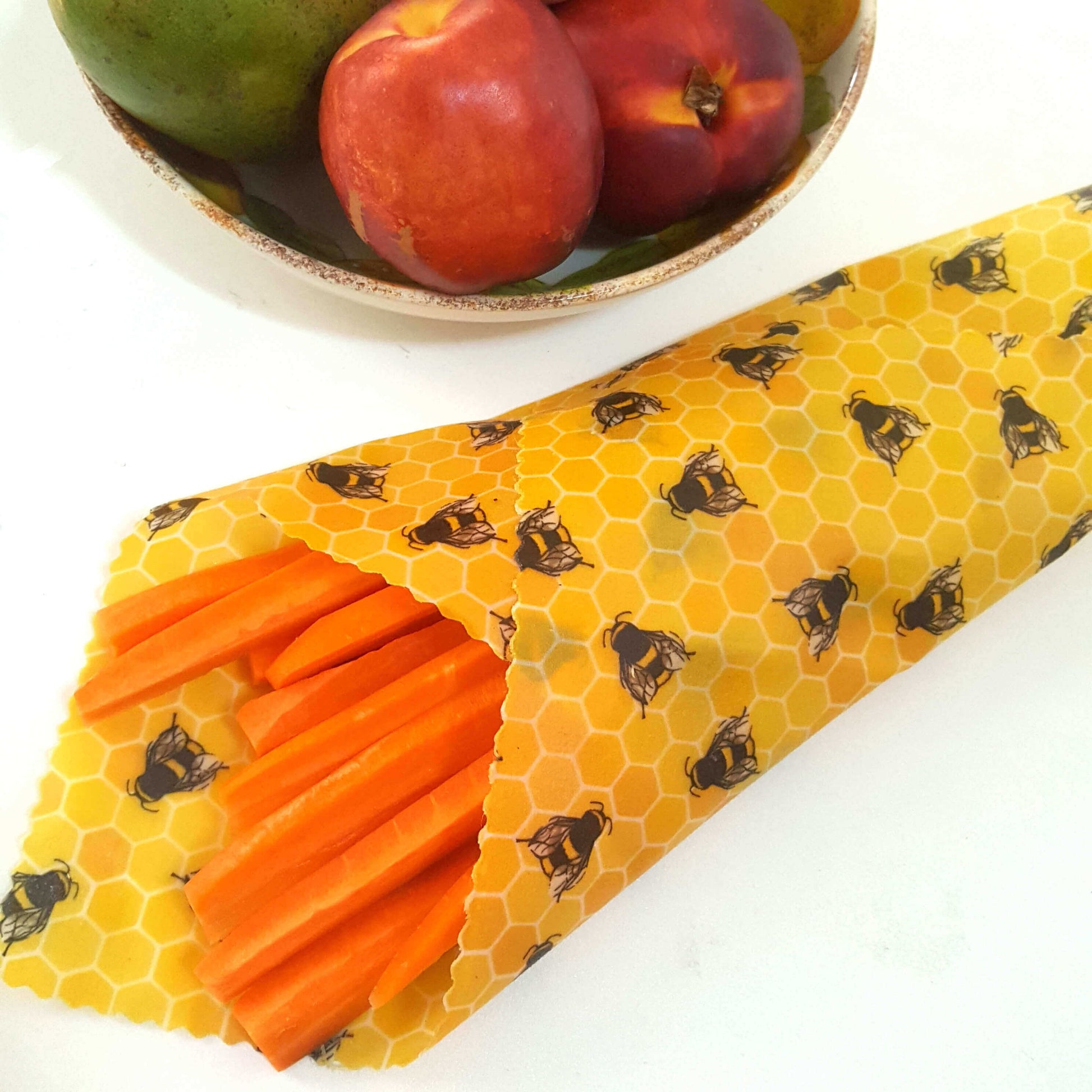 Reusable Beeswax Food Wraps 100% Hand Made in the UK by Honey Bee Good. Planet-Kind single large beeswax wrap in Yellow Bees pattern as flatlay with carrots
